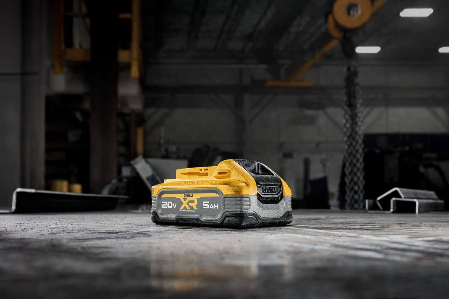 Un paquete de batería de iones de litio DEWALT 20V XR (modelo DCBP520) con capacidad de 5,0Ah está colocado sobre una superficie de taller. La batería es amarilla y negra y está diseñada para usarse con herramientas eléctricas DEWALT.