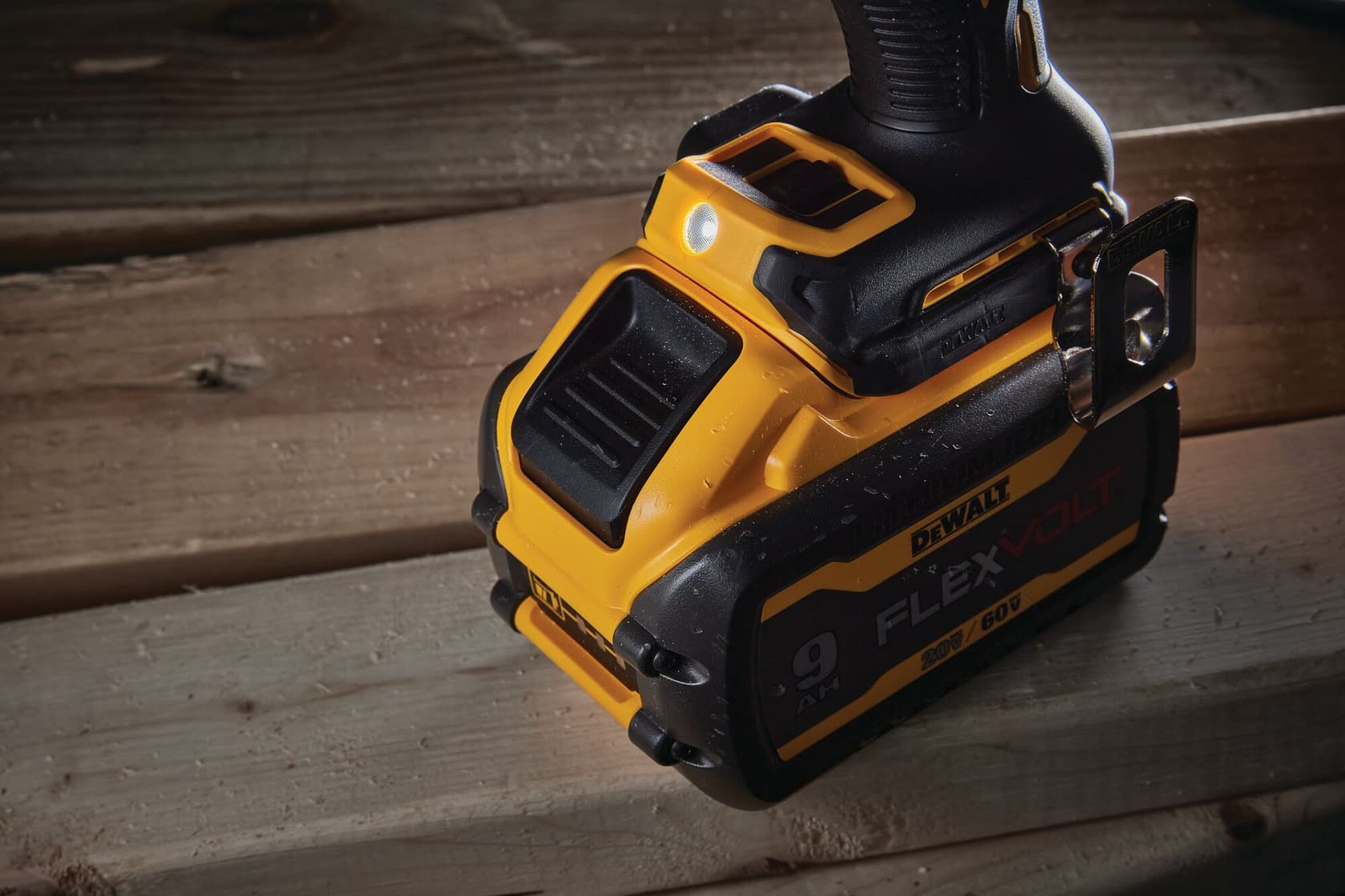 Imagen en primer plano de una herramienta eléctrica inalámbrica DEWALT equipada con una batería FLEXVOLT de 9Ah, colocada sobre una superficie de madera.