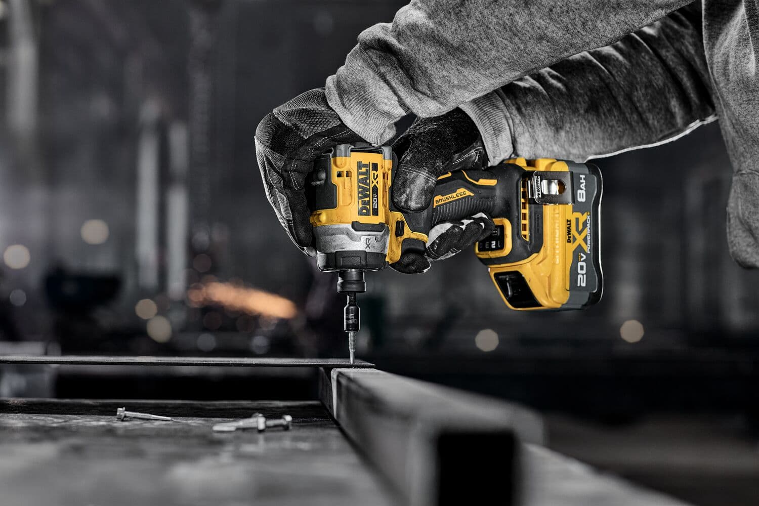 Persona usa un destornillador de impacto DEWALT inalámbrico para atornillar en metal en taller industrial.