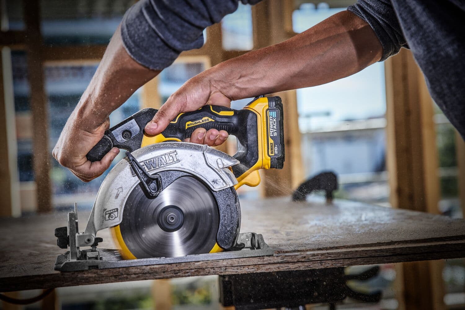 Una persona utiliza una sierra circular inalámbrica DEWALT para cortar un trozo de madera, produciendo aserrín en un entorno de construcción.