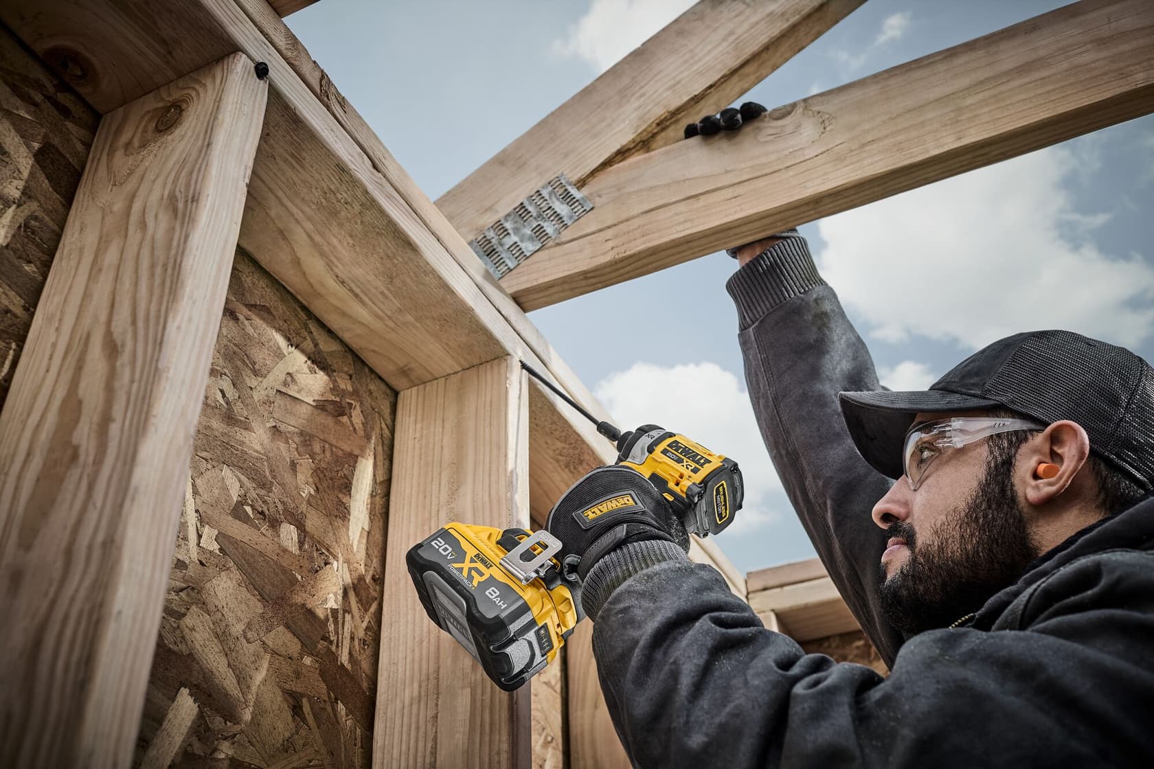 Persona usando destornillador de impacto DEWALT inalámbrico para atornillar vigas de madera en construcción.