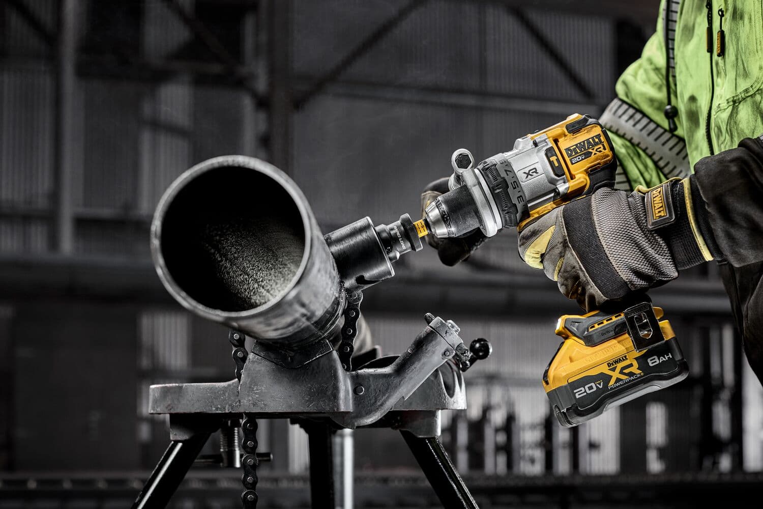 Una herramienta DEWALT corta un tubo metálico en un entorno industrial, manejada por un operario con guantes.