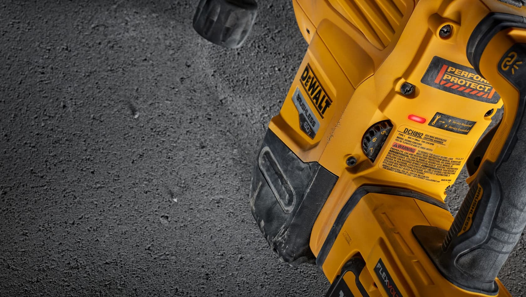 Primer plano de una herramienta eléctrica DEWALT con carcasa amarilla, mostrando botones de control y etiquetas de seguridad. La herramienta está sobre una superficie gris rugosa.