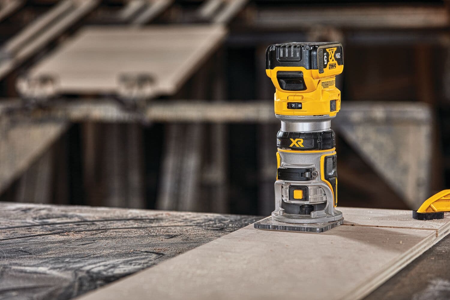 Un enrutador compacto inalámbrico DEWALT (modelo DCW600B) se muestra de pie sobre una superficie de madera en un taller.