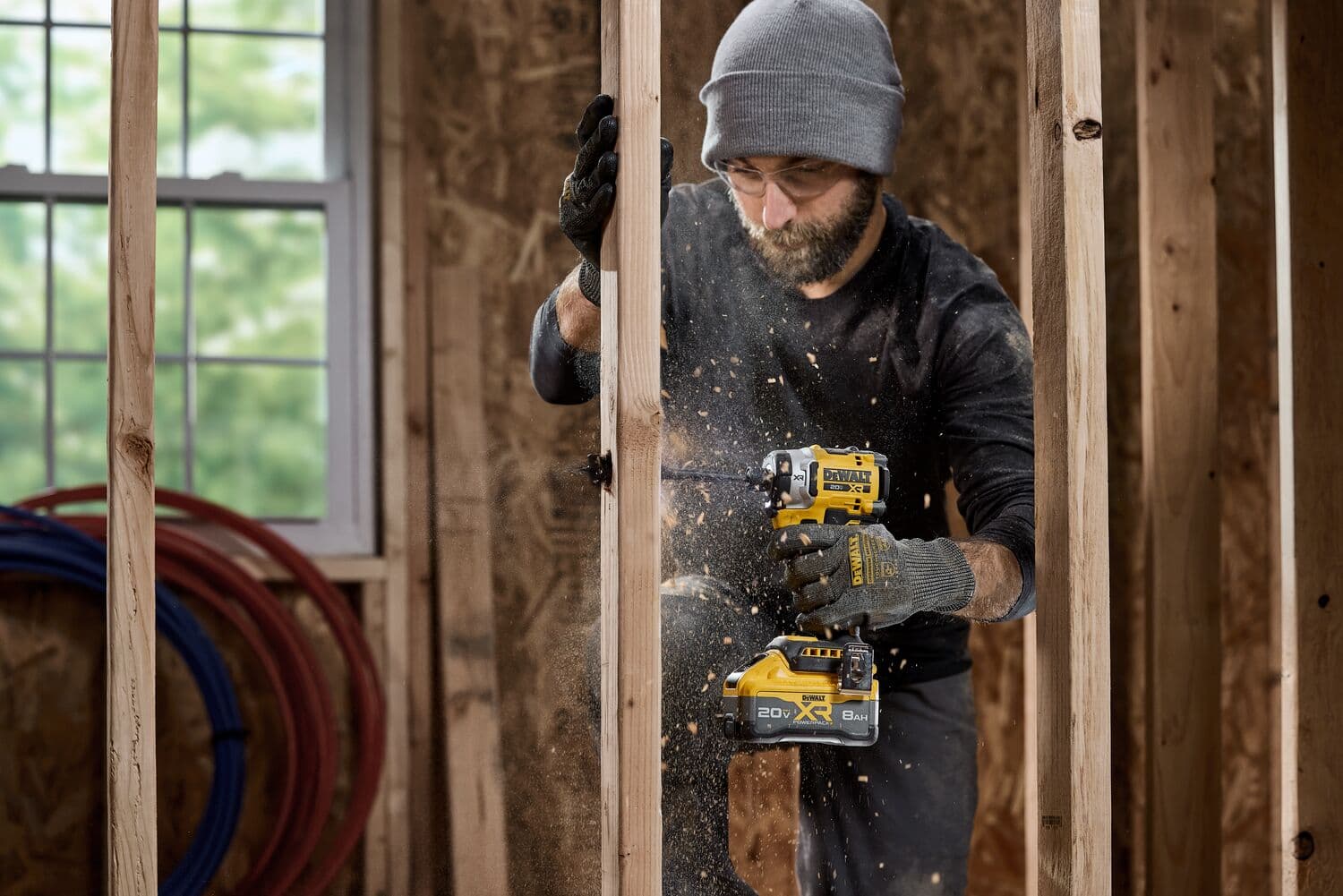 Persona usando DEWALT DCF860B en construcción, polvo de madera, con guantes y gorro.