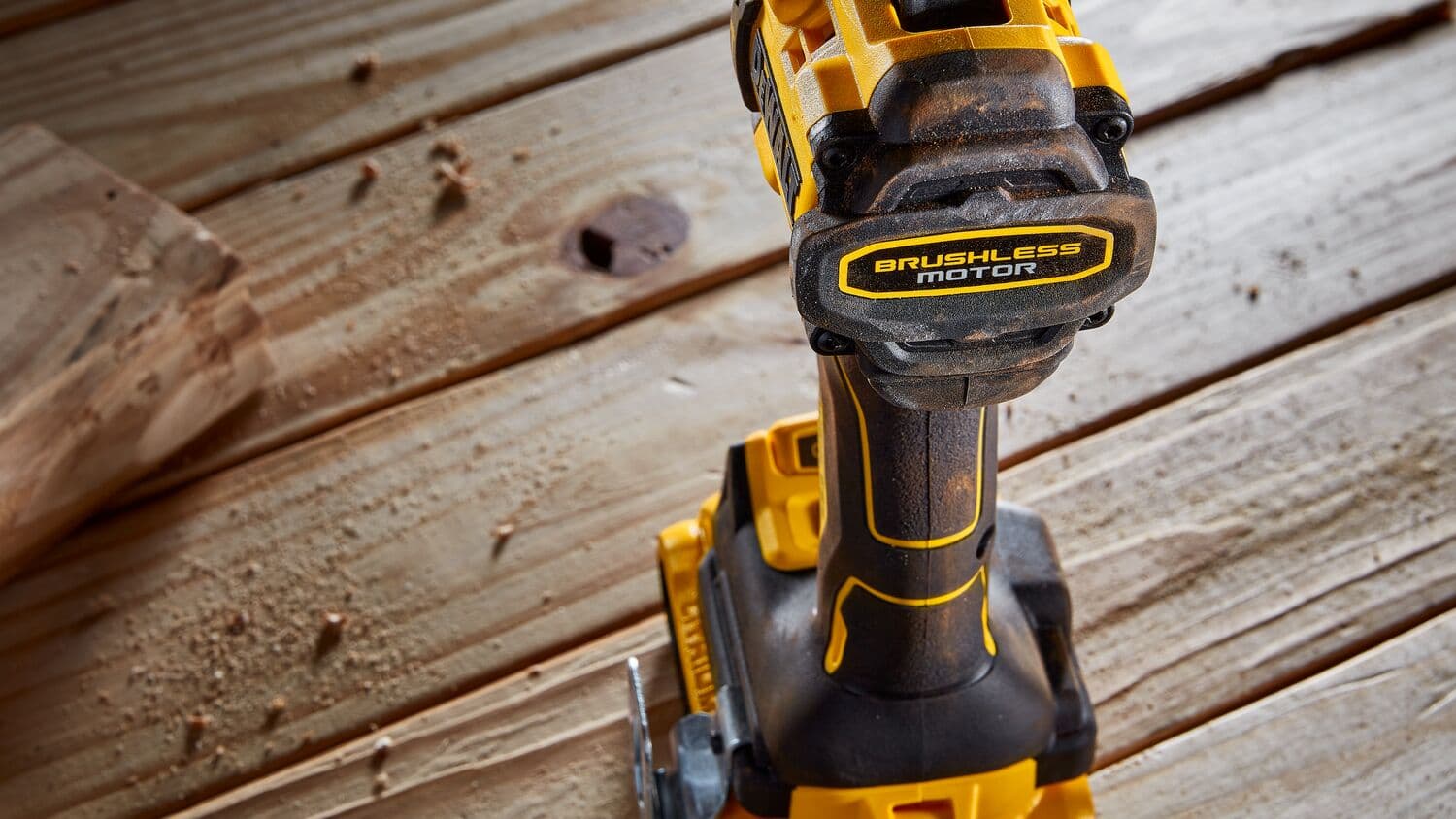 Primer plano de un taladro inalámbrico DEWALT con motor sin escobillas sobre una superficie de madera con aserrín.