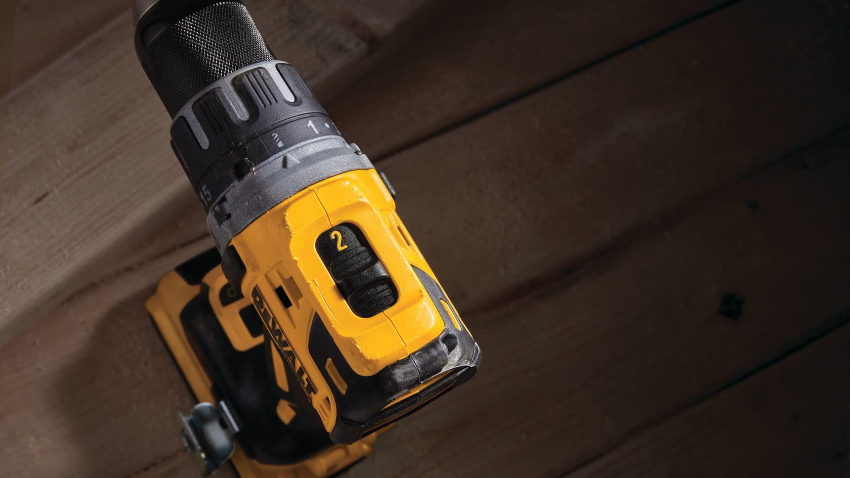 Primer plano de un taladro inalámbrico DEWALT mostrando el dial de ajuste y el selector de velocidad sobre un fondo de madera.
