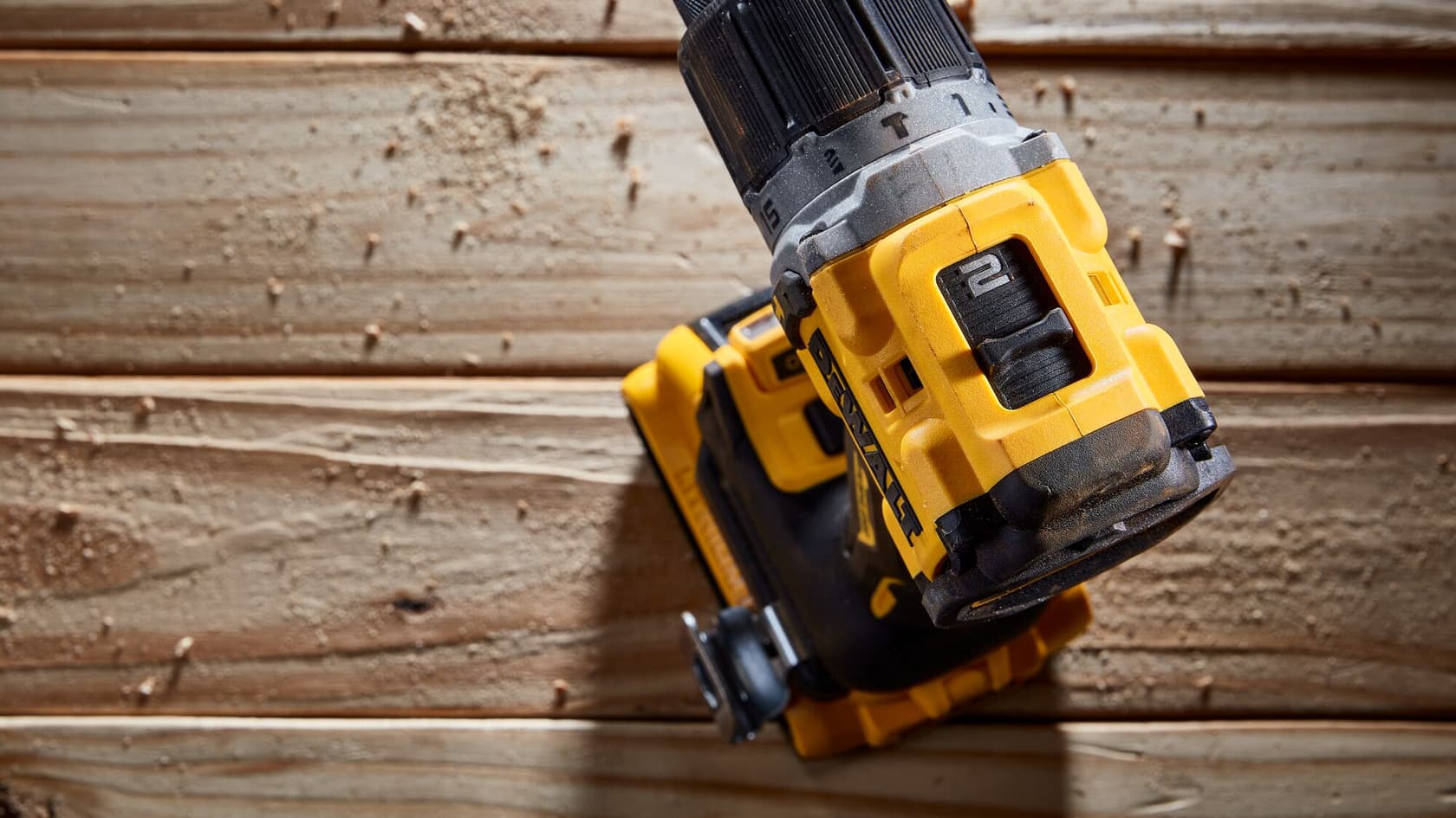 Vista de cerca de un taladro inalámbrico DEWALT en uso, colocado sobre una superficie de madera con aserrín alrededor.