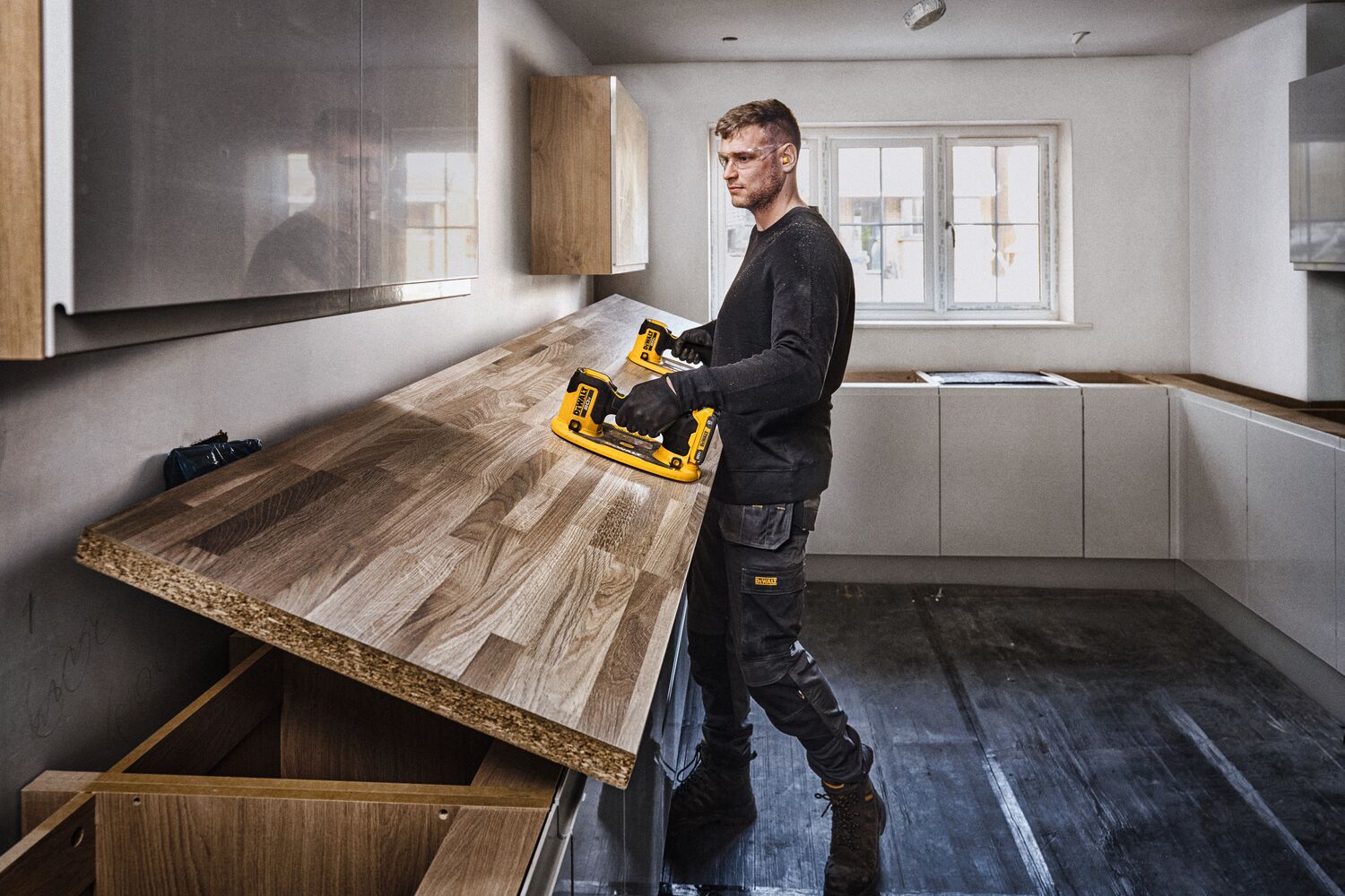 User lifting butcher block with pair of DEWALT 20V MAX Grabo Lifter