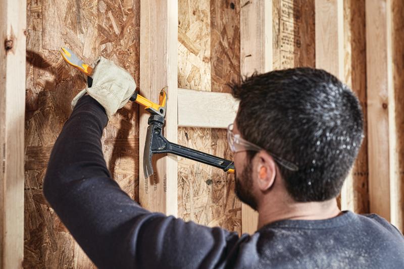 12 inch Precision Claw Bar being used with hammer by a person to pull nail from wood.