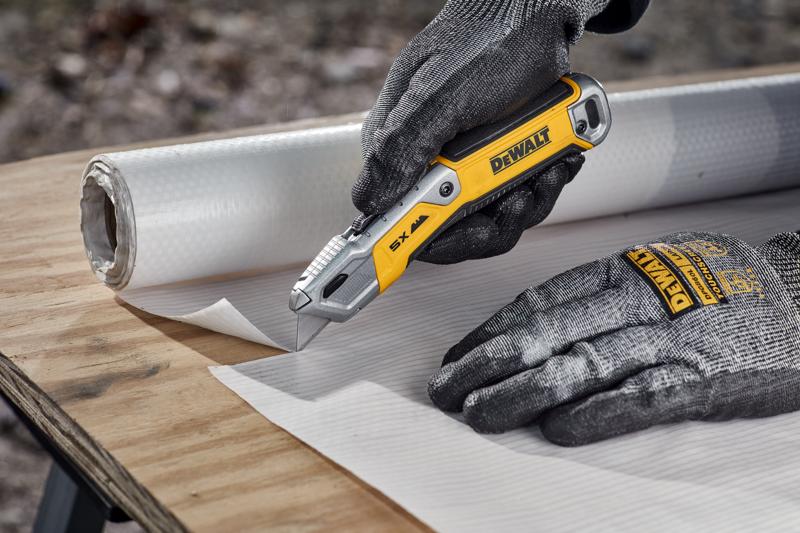 Worker cutting house wrap on plywood surface with DEWALT® DWHT10998 Utility Knife