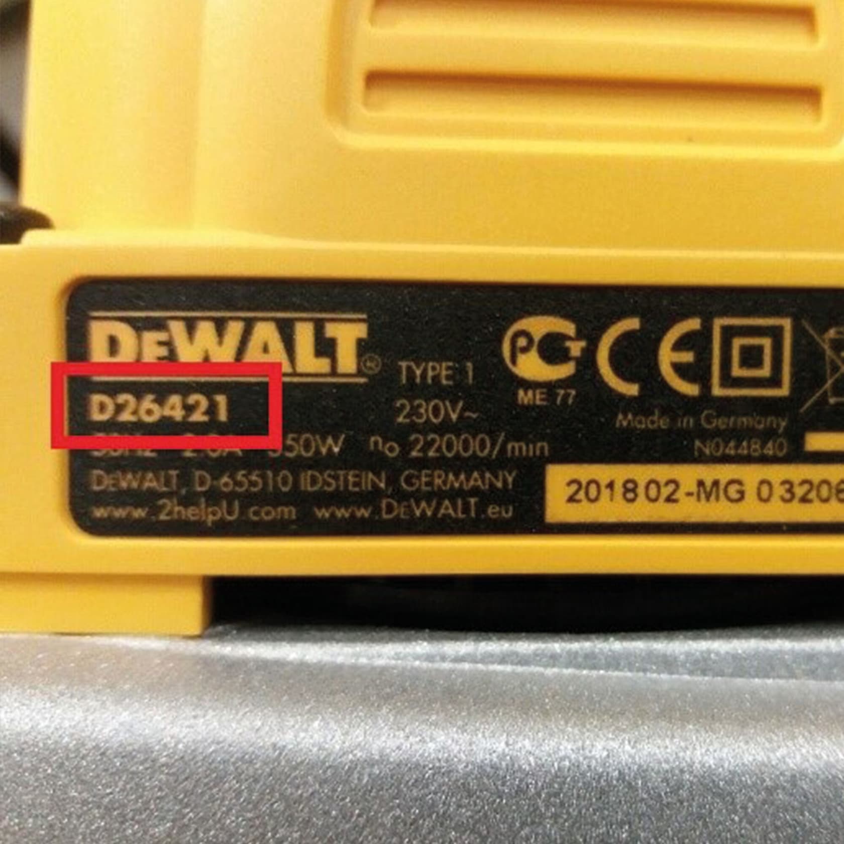 Primer plano de la etiqueta de una herramienta eléctrica DEWALT, con el número de modelo D26421 resaltado en rojo. La etiqueta incluye especificaciones como voltaje, potencia y marcas de certificación, así como información de fabricación de Alemania.